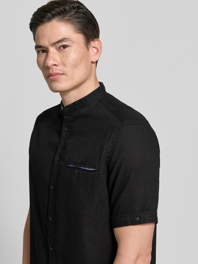 Männermodel trägt Regular Fit Freizeithemd mit Brusttasche von Christian Berg Men, Reine Baumwolle, Stehkragen, durchgehende Knopfleiste, Kurzärmelig, schwarze Farbe, glatte Textur, Nahaufnahme Oberkörper.