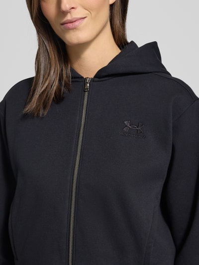 Frauenmodel trägt Sweatjacke mit Label-Stitching von Under Armour, Schwarz, Baumwoll-Mix, Regular-Fit, Kapuze, Reißverschluss, Eingrifftaschen, Nahaufnahme Oberkörper.