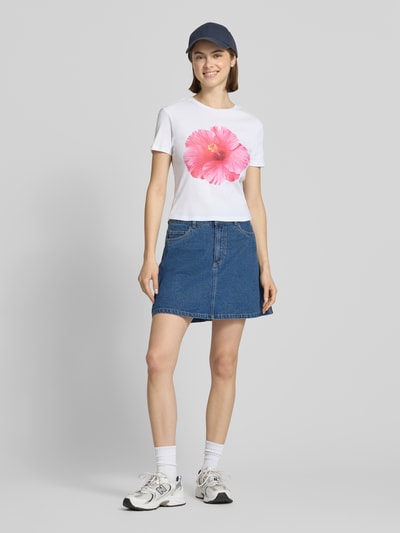 Frauenmodel trägt Regular Fit T-Shirt aus reiner Bio-Baumwolle Modell 'PRINCESS' von Only in Optik: Unifarben mit Fotoprint, Denimrock, Weiß und Blau dominieren, Materialverarbeitung Jersey, Ganzkörperansicht von vorne.