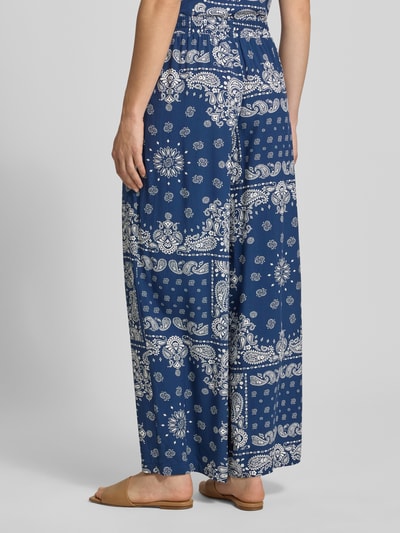 Frauenmodel trägt Relaxed Fit Weite Hose aus reiner Viskose Modell 'KAVI' von Only, blau mit weißem Muster, Damen Hose, Ganzkörperansicht Rückansicht.
