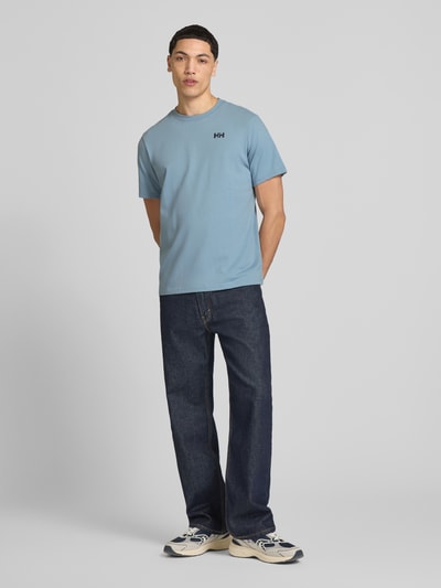 Männermodel trägt Herren T-Shirt mit Logo-Motiv-Print Modell 'SHORELINE' von Helly Hansen, Reine Baumwolle, Gerader-Schnitt, Rundhalsausschnitt, Rückenlänge 70 cm, Ganzkörperansicht von vorne.