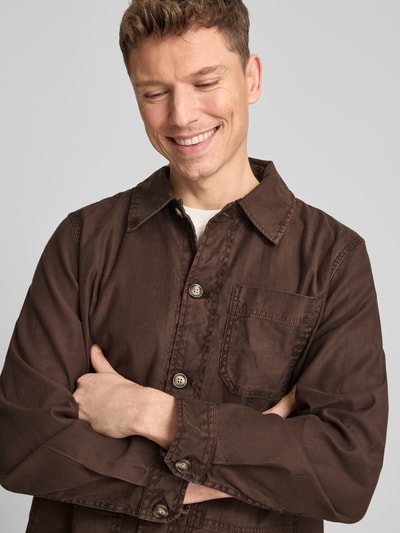 Männermodel trägt Regular Fit Hemdjacke aus Leinen-Mix von Gant, Braun mit Umlegekragen, Knopfleiste, Aufgesetzte Taschen, Nahaufnahme Oberkörper. Rückenlänge bei Größe M: 76 cm, Leinen-Mix mit Baumwoll-Anteil.
