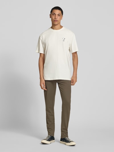 Männermodel trägt Slim Fit Chino aus Viskose-Mix Modell 'MARK' von ONLY & SONS, braun, kombiniert mit weißem Shirt, Ganzkörperansicht von vorne.