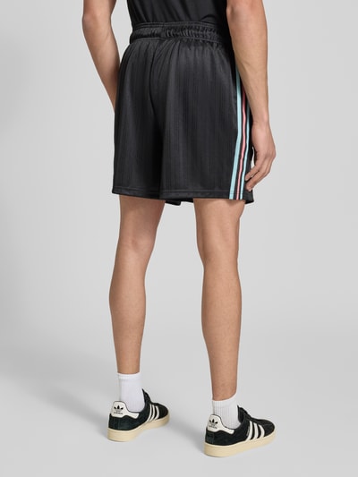 Männermodel trägt Regular Fit Sweatpants mit Label-Detail Modell 'Belgien 26' von adidas Originals in Schwarz, Ganzkörperansicht Rückansicht.