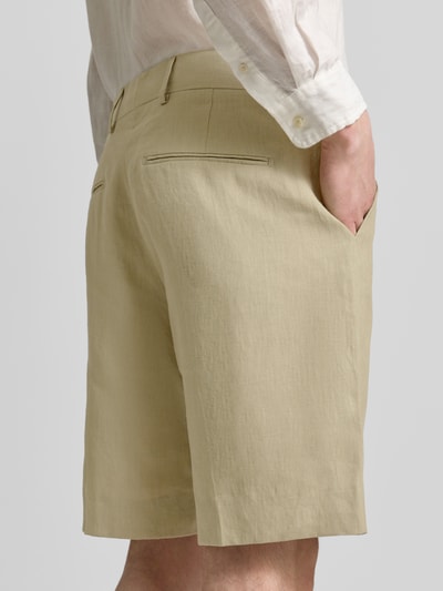 Männermodel trägt beige Shorts mit französischen Eingrifftaschen Modell 'Troy' von Tiger Of Sweden, Leinenstruktur, Ganzkörperansicht Rückansicht. Gerader Schnitt, Haken-, Knopf- und Reißverschluss, Gesäßtaschen, Bundweite 43 cm, Innenbeinlänge 23 cm bei Größe 50.
