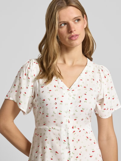 Frauenmodel trägt Minikleid aus reiner Viskose Modell 'EVIDA' von Only mit Allover-Muster, V-Ausschnitt, Knopfleiste, Taillengürtel, Kurzarm, Ganzkörperansicht von vorne.
