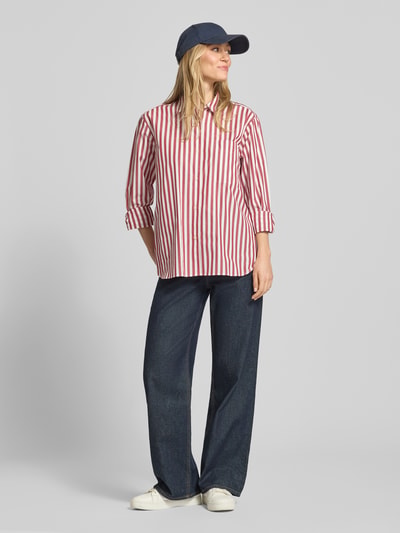Frauenmodel trägt Regular Fit Langarmbluse aus reiner Baumwolle von Tommy Hilfiger, Optik:Allover-Muster, Streifen-Optik, Popeline, Logo-Stitching, Hemdkragen, einreihige Knopfleiste, Brusttasche, Langarm, Manschette, abgerundeter Rumpfabschluss, Regular-Fit, Unifarben und gestreift, Ganzkörperansicht von vorne.