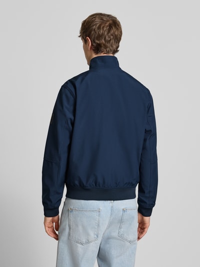 Männermodel trägt Regular Fit Bomberjacke mit Stehkragen Modell 'Parker' von Jack & Jones in Dunkelblau, Ganzkörperansicht Rückansicht. Softshell-Material, elastische Bündchen, Napoleontasche, Eingrifftaschen mit Druckknopfverschluss, Rückenlänge 67 cm, Schulterbreite 43 cm, Brustweite 55 cm, Ärmellänge 65 cm.