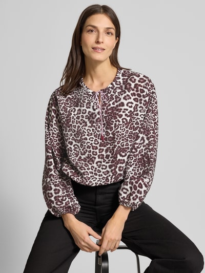 Kobiece model prezentuje Regular Fit Bluzka z mieszanki wiskozy ze zwierzęcym nadrukiem na całej powierzchni od Marc Cain, dekolt z lamówką, długie rękawy, wykończenie elastyczne, długość tyłu w rozmiarze 36: 54 cm, długość rękawa w rozmiarze 36: 53 cm, widok z przodu na górną część ciała.