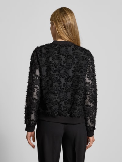 Frauenmodel trägt semitransparenten Blouson Modell 'Pi44nioa' von ZABAIONE in Schwarz, florale Struktur, Ganzkörperansicht Rückansicht.