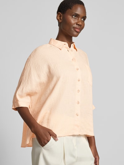 Frauenmodel trägt Relaxed Fit Leinenbluse mit Brusttasche von Emily Van den Bergh in Apricot, Hemdblusenkragen, 3/4-Arm, reine Leinen, Ganzkörperansicht von vorne. Rückenlänge bei Größe S/M: 63 cm, Ärmellänge 33 cm.