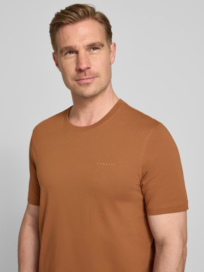 Männermodel trägt T-Shirt mit Label-Detail von bugatti in Braun, reine Baumwolle, gerader Schnitt, Nahaufnahme Oberkörper.