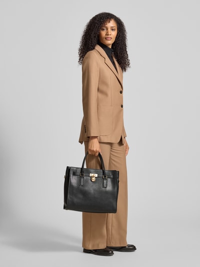 Frauenmodel trägt Handtasche mit Tragehenkel Modell 'HAMILTON' von MICHAEL Michael Kors in Schwarz, Hauptfach mit Reißverschluss, Label-Detail, Breite 37 cm, Länge 32 cm, Tiefe 12 cm, Schulterriemen 47 cm, Ganzkörperansicht von vorne.