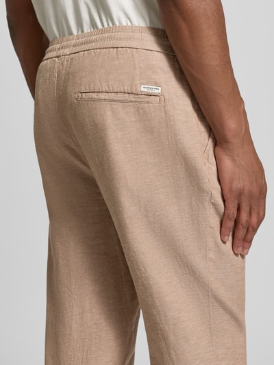 Männermodel trägt Hose mit Leinen-Anteil und französischen Eingrifftaschen von Scotch & Soda, beigefarbener Baumwoll-Mix, Detailaufnahme Rückansicht. Gerader Schnitt, elastischer Bund mit Kordelzug, Gesäßtaschen und typischer Struktur.