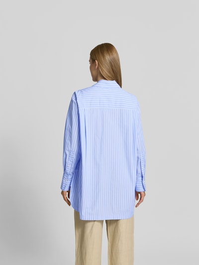 Frauenmodel trägt Relaxed Fit Hemdbluse aus Baumwolle von Joseph in Hellblau mit weißen Streifen, verlängerte Rückseite, Ganzkörperansicht Rückansicht.