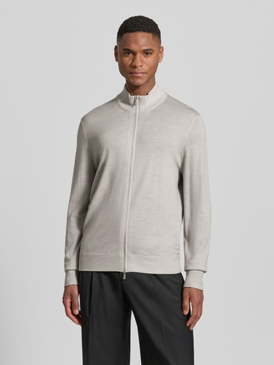 Męski model nosi Strickjacke aus Schurwolle mit Zweiwege-Reißverschluss od GRAN SASSO, jasnoszary kolor, proste rękawy, stójka, gładka faktura, krój prosty, całkowita długość pleców 66 cm, długość rękawa 67 cm, widok całej sylwetki z przodu.