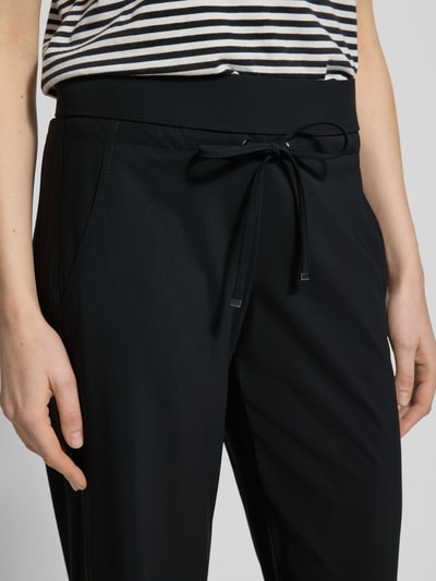 Frauenmodel trägt Straight Leg Jogpants aus Hightech Jersey Modell 'CANDICE' von Raffaello Rossi mit Elastikbund und Schnürung, Nahaufnahme Oberkörper, Material wirkt glatt und matt, Bundweite 40 cm, Innenbeinlänge 84 cm, Damen Jogpants.