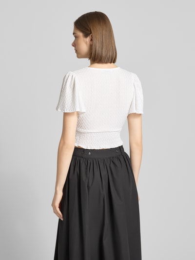Vrouwenmodel draagt Regular Fit Crop Top met structuurpatroon model 'HANNAH' van Only, uni, v-hals, smock onderbust, schmetteringsmouwen, kort, zwart-wit, volledige lichaamsweergave achterkant.