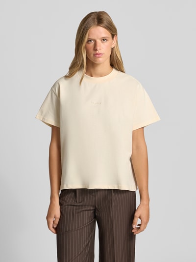 Frauenmodel trägt T-Shirt mit Logo-Stitching Modell 'Ella' von OH APRIL, reine Baumwolle, Boxy Fit, Rundhalsausschnitt, Ganzkörperansicht von vorne.
