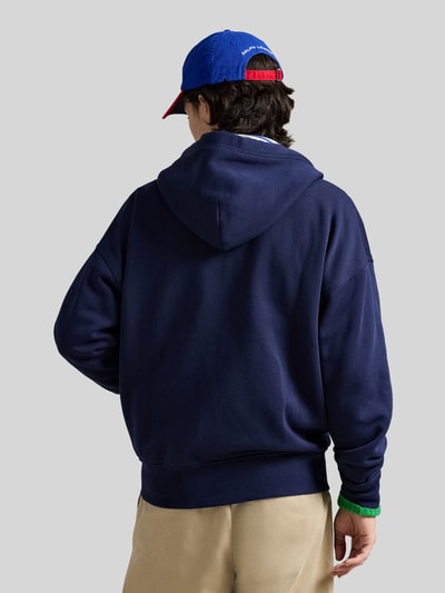 Männermodel trägt Relaxed Fit Sweatjacke aus Baumwoll-Mix von Polo Ralph Lauren in Dunkelblau mit Kapuze, Ganzkörperansicht Rückansicht.