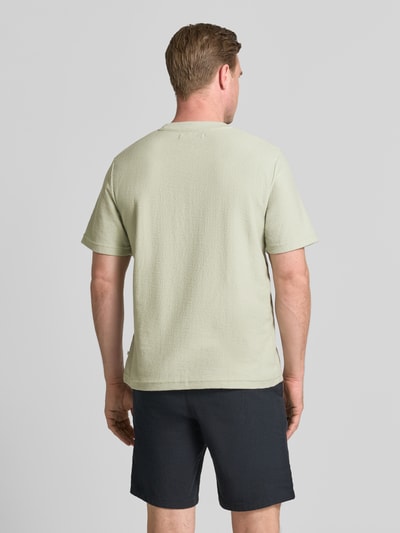 Männermodel trägt T-Shirt mit Rundhalsausschnitt Modell 'ODIN' von Samsøe Samsøe in Hellgrün, Baumwoll-Mix, Regular-Fit, mit Label-Detail, Rückenlänge bei Größe M 70 cm, Ganzkörperansicht Rückansicht.