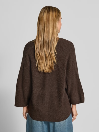 Männermodel trägt Oversized Cardigan aus bawełna i inne włókna Model 'DAMSVILLE' od American Vintage, elastyczna mieszanka materiałów, krój oversized fit, imitacja dzianiny, listwa guzikowa, dekolt w serek, długość tyłu w rozmiarze XS/S 63 cm, długość rękawów 35 cm, widok całej sylwetki z tyłu.