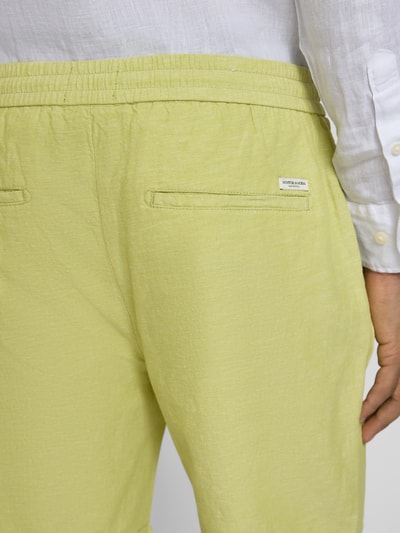 Mężczyznamodel nosi Shorts mit elastischem Bund od Scotch & Soda, mieszanka bawełny i lnu, krój regular fit, kolor jasnożółty, detal tylnej części, zbliżenie na pas.