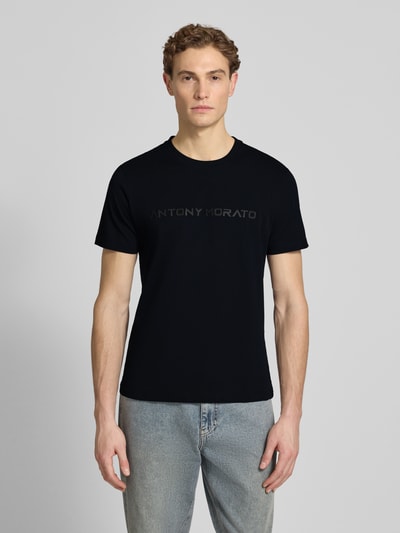 Männermodel trägt T-Shirt mit Label-Print von Antony Morato in Schwarz, reine Baumwolle, gerader Schnitt, Ganzkörperansicht von vorne.