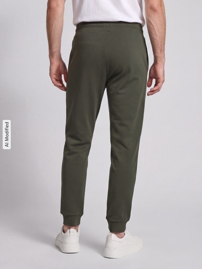 Mężczyzna nosi Regular Fit Sweathose aus Baumwoll-Mix model 'Laze Pants CW' od HUGO, zielony kolor, tekstura gładka, Ganzkörperansicht Rückansicht, KI-modifiziertes Bild. Spodnie dresowe męskie od HUGO.