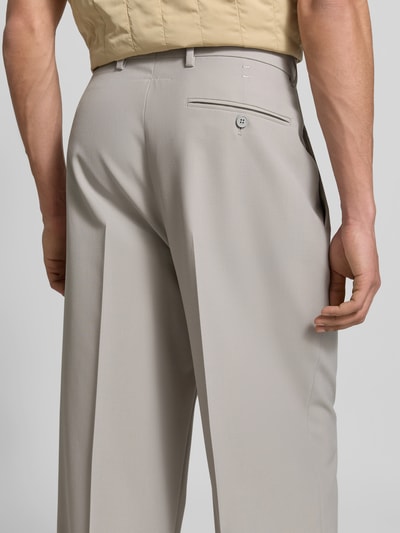 Männermodel trägt Anzughose mit Schurwoll-Anteil von MM6 Maison Margiela in Beige, Bügelfalten, Gesäßtasche, Straight Fit, Nahaufnahme Rückansicht.