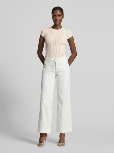Frauenmodel trägt T-Shirt in Pointelle-Optik mit Rundhalsausschnitt von Guess aus Viskose-Mix im Körpernaher-Schnitt in Beige, Ganzkörperansicht von vorne.