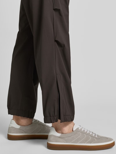 Männermodel trägt Relaxed Fit Hose mit Bundfalten Modell 'Lirog' von Drykorn aus Elastischer-Material-Mix, Detailaufnahme Innenbeinlänge. Herren HOSE, Bundweite 41 cm, Eingriffstaschen, Gesäßtasche, Knopf-Reißverschluss, Farbe dunkelbraun, matte Textur.