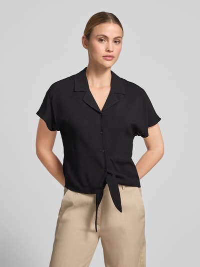 Frauenmodel trägt Regular Fit Bluse aus Reine Viskose mit Knotendetail Modell 'RADIA' von Soyaconcept, Reverskragen, Knopfleiste, Rückenlänge bei Größe S 55 cm, Ärmellänge bei Größe S 10 cm, einfarbig schwarz, glatte Oberfläche, Ganzkörperansicht von vorne.