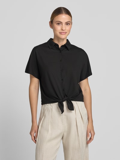 Frauenmodel trägt Regular Fit Hemdbluse aus Viskose-Mix Modell 'Suruli' von OPUS in Schwarz mit Hemdblusenkragen, Ärmelloses-Design, durchgehender Knopfleiste und Zierknoten, Rückenlänge 50 cm, Ärmellänge 21 cm, Nahaufnahme Oberkörper.