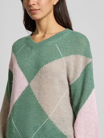 Frauenmodel trägt Wollpullover mit gerippten Abschlüssen von Fynch-Hatton im Material-Mix mit Woll-Anteil, lockerer Schnitt, V-Ausschnitt, grün-pink-beige, Nahaufnahme Oberkörper.