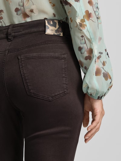 Frauenmodel trägt Flared Fit Jeans mit Lyocell-Anteil von Marc Cain in Dunkelbraun, elastischer Material-Mix, 5-Pocket-Design, Nahaufnahme Rückansicht.