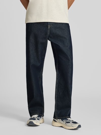 Männermodel trägt Wide Fit Jeans aus reiner Baumwolle Modell 'Alex' von JACK & JONES in Dunkelblau, 5-Pocket-Design, Ganzkörperansicht von vorne.