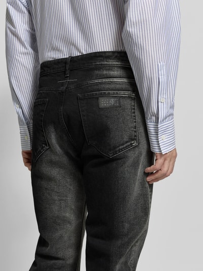 Männermodel trägt Straight Fit Jeans aus reiner Baumwolle von MM6 Maison Margiela im Used-Look, 5-Pocket-Design, Nahaufnahme Rückansicht.