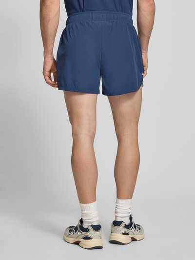Männermodel trägt Shorts mit elastischem Bund Modell 'ERUDITO' von Ellesse, Herren Shorts aus Material-Mix mit Stretch-Anteil, Regular-Fit, dunkles Blau, glatte Struktur, Ganzkörperansicht Rückansicht.