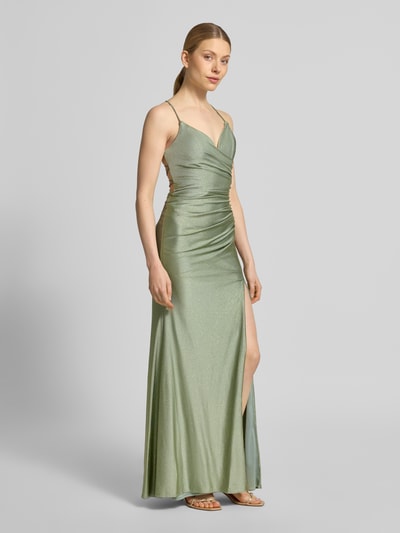 Frauenmodel trägt Maxikleid mit Drapierungen und Gehschlitz von Mascara, schimmernder Satin in Hellgrün, figurbetonter Schnitt, Ganzkörperansicht von vorne.