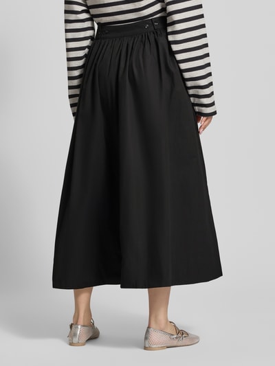 Frauenmodel trägt schwarzen Midirock mit A-Linie aus reiner Baumwolle, Modell 'SALLY' von Topshop, seitlicher Reißverschluss, Ganzkörperansicht Rückansicht. Bundweite bei Größe 36: 35 cm.