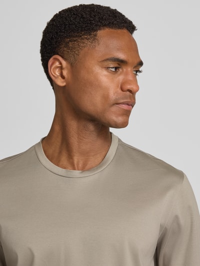 Männermodel trägt T-Shirt mit Rundhalsausschnitt von bugatti in Beige, schlichte Form, glatte Baumwollstruktur, Nahaufnahme Oberkörper.