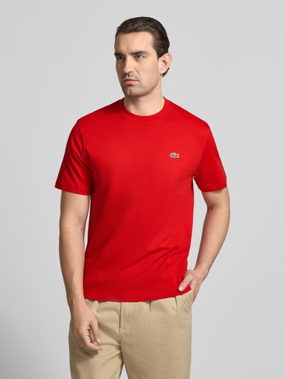 Męski model nosi Regular Fit Poloshirt aus reiner Baumwolle von Lacoste, efekt: jednolity kolor, krój regular fit, wyhaftowane logo, okrągły dekolt, krótki rękaw, bawełna, całkowity widok z przodu.