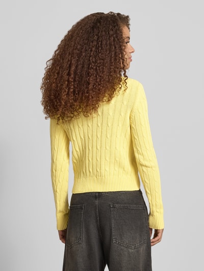 Frauenmodel trägt Strickpullover mit Zopfmuster und Label-Stitching von REVIEW in Gelb, Baumwoll-Mix, Regular-Fit, Rückenlänge 52 cm, Ganzkörperansicht Rückansicht.