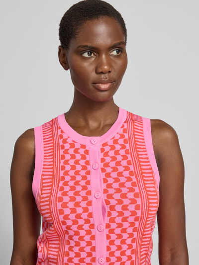 Frauenmodel trägt Strickweste aus Viskose-Mix Modell 'GABLESI' von SUNCOO PARIS in Pink-Rot mit Knopfleiste, Nahaufnahme Oberkörper.