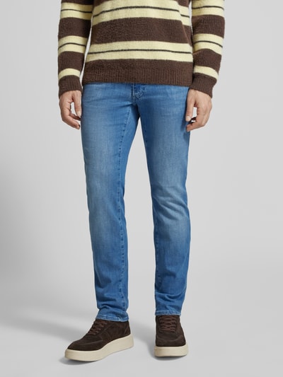 Männermodel trägt Slim Fit Jeans mit Eingrifftaschen Modell 'Chuck' von BRAX, Baumwoll-Elasthan-Mix, blaue Farbe, Ganzkörperansicht von vorne.