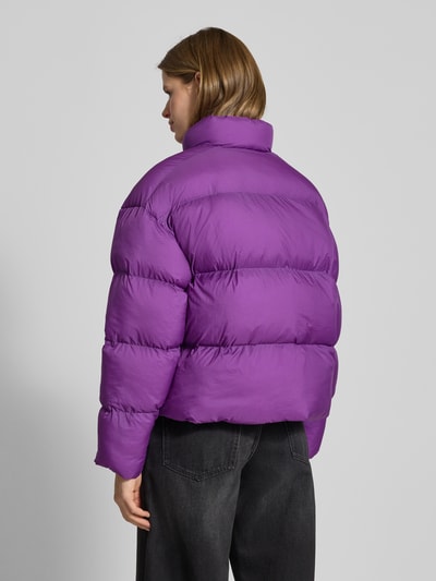 Vrouwenmodel draagt Steppjacke mit Label-Print - PUMA X P&C*, recht model, effen paars, recht model, met opstaande kraag, zoom tot taille, rugaanzicht, context: dames steppjacke van PUMA X P&C*, recht model, label-print, effen design, opstaande kraag, rits, steekzakken, ruglengte maat M 56 cm, schouderbreedte 60 cm, borstwijdte 60 cm, mouwlengte 55 cm.