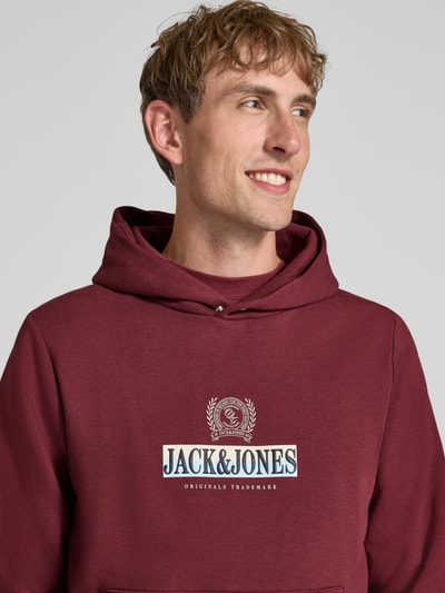Männermodel trägt Hoodie mit Label-Print Modell 'FREDERIKSBERG' von JACK & JONES in Dunkelrot, Baumwoll-Mix, Nahaufnahme Oberkörper.