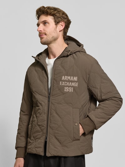 Männermodel trägt Jacke mit Steppnähten und Label-Detail von Armani Exchange in Braun mit Kapuze, Zweiwege-Reißverschluss, Nahaufnahme Oberkörper.