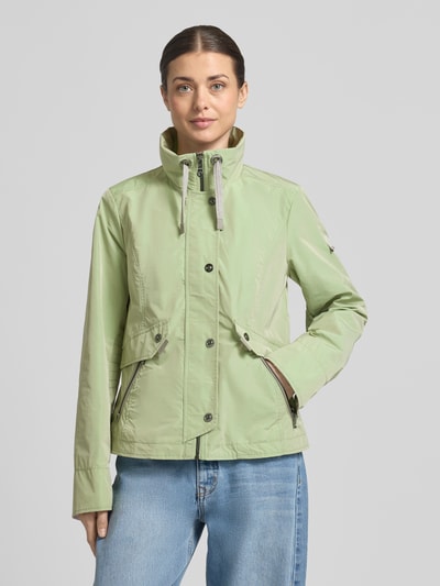 Frauenmodel trägt Regular Fit Jacke mit Logo-Patch von Gil Bret in hellem Grün, Stehkragen mit Tunnelzug, Reißverschlusstaschen, glatte Struktur, Ganzkörperansicht von vorne, Rückenlänge 64 cm, Schulterbreite 41 cm, Brustweite 46 cm, Ärmellänge 65 cm.